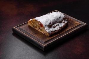 Christmas pie stollen with marzipan, berries and nuts on a dark concrete background photo