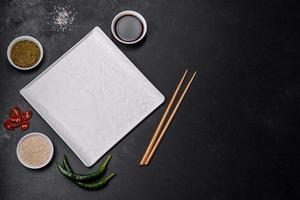 Empty plate with wooden sticks for Asian food on a dark concrete background photo