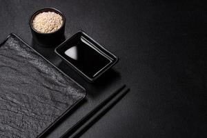Empty plate with wooden sticks for Asian food on a dark concrete background photo