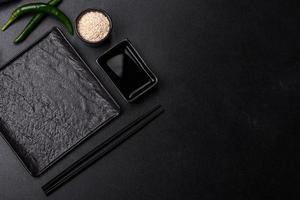 Empty plate with wooden sticks for Asian food on a dark concrete background photo