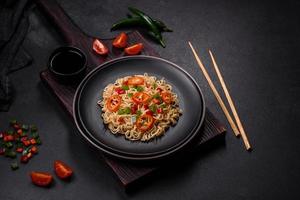 Delicious fresh noodles with sweet pepper, tomato, spices and herbs photo