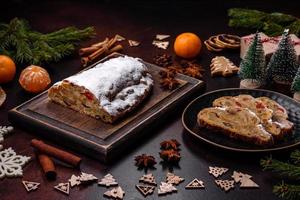 Christmas pie stollen with marzipan, berries and nuts on a dark concrete background photo