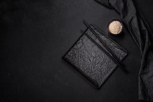 Empty plate with wooden sticks for Asian food on a dark concrete background photo