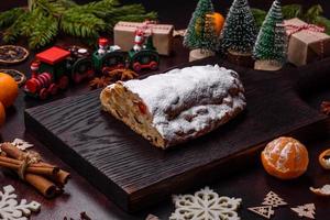 Christmas pie stollen with marzipan, berries and nuts on a dark concrete background photo