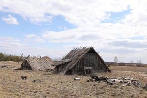 remnants of Ancient houses made from hollow logs with wooden and thatched roofs on the meadow photo