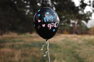 celebración fiesta de género en la naturaleza. globo negro con la inscripción niño y niña moviéndose en el aire. los futuros padres están teniendo una fiesta de revelación de género. esperando un bebé. fiesta de bienvenida al bebé foto