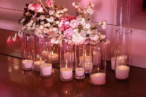 Wedding decor, burning candles in glass flasks with flowers composition on the floor. Coziness and style. Modern event design. selective focus. photo