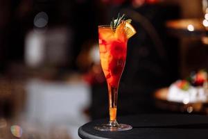 Fresh colorful exotic alcoholic cocktail with orange and rosemary on the bar desk. Tasty Soft drink with fruits. selective focus photo