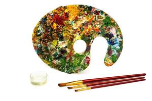 Palette with colorful paints. Colorful oil painting palette with a brush reaching in. Paint brushes and paints for drawing. photo