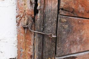 a fragment of an old wooden door made of boards covered with peeling and cracked green paint. The door has a handle, latch and door trim. photo