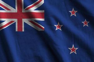 New Zealand flag with big folds waving close up under the studio light indoors. The official symbols and colors in banner photo