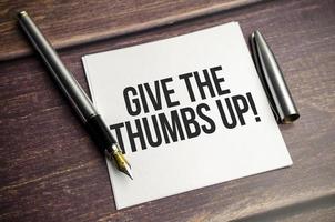 give the thumbs up words on wooden background photo