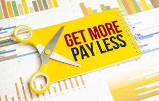 get more pay less. Text on yellow notebook and charts photo