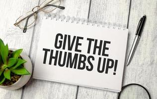 give the thumbs up - written on paper notebook and office supplies photo