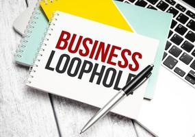 business loophole words on colourful notebooks with laptop and pen photo