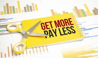 get more pay less. Text on yellow notebook and charts photo