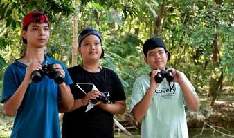 los niños del sudeste asiático están usando binoculares para observar aves en el bosque tropical, idea para aprender criaturas y animales salvajes fuera del aula. foto