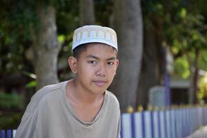 Portrait young southeast asian islamic or muslim boy in white shirt and hat, isolated on white, soft and selective focus. photo