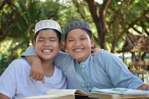 Asian muslim boys sit together in school park to read and learn their daily activity and do homework in their free times before going back home, soft and selective focus. photo