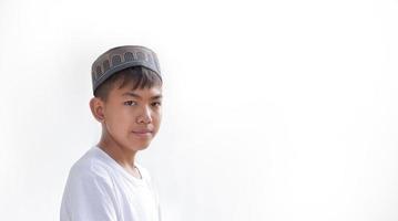 Portrait young southeast asian islamic or muslim boy in white shirt and hat, isolated on white, soft and selective focus. photo