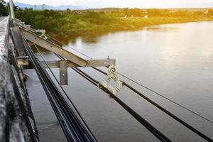 Hanging and keeping the storage of high voltage cables and fiber optic cables in the side of concrete river bridges in the remote areas of Southeast Asia, soft and selective focus. photo