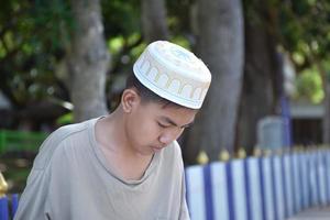 retrata a un joven islámico o musulmán del sudeste asiático con camisa blanca y sombrero, aislado en un enfoque blanco, suave y selectivo. foto