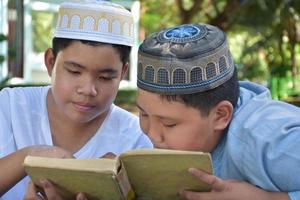 los niños musulmanes asiáticos se sientan juntos en el parque escolar para leer y aprender su actividad diaria y hacer la tarea en sus tiempos libres antes de volver a casa, enfoque suave y selectivo. foto