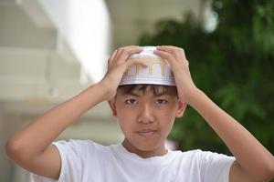 retrata a un joven islámico o musulmán del sudeste asiático con camisa blanca y sombrero, aislado en un enfoque blanco, suave y selectivo. foto