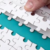 The human hand paves the way to the surface of the jigsaw puzzle, forming a blue space. The concept of overcoming the difficulties on the way to success photo