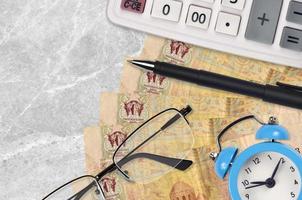 2 Ukrainian hryvnias bills and calculator with glasses and pen. Business loan or tax payment season concept. Time to pay taxes photo