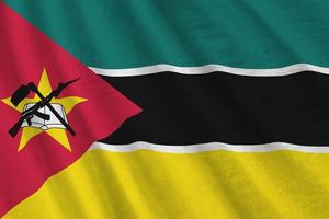 Mozambique flag with big folds waving close up under the studio light indoors. The official symbols and colors in banner photo