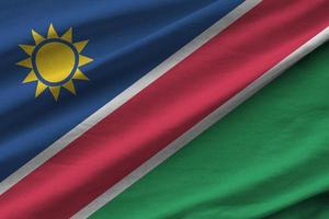 Namibia flag with big folds waving close up under the studio light indoors. The official symbols and colors in banner photo