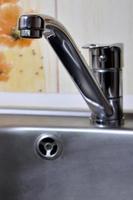 Empty clean silvery kitchen sink and water faucet close up photo