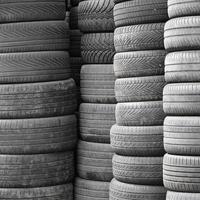 Neumáticos usados viejos apilados con montones altos en el garaje secundario de la tienda de piezas de automóviles foto