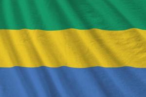 Gabon flag with big folds waving close up under the studio light indoors. The official symbols and colors in banner photo