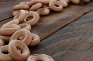 A lot of fresh yellow bagels lie on the surface of the old dark wood. A popular kind of flour products. One of the traditional Russian treats for tea photo