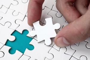 The human hand fills the last missing elements of the surface from the jigsaw puzzle. The concept of the completion of the initiated cases photo