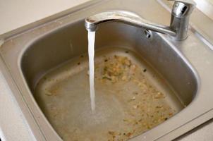 Stainless steel sink plug hole close up full of water and particles of food photo