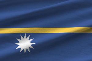 Nauru flag with big folds waving close up under the studio light indoors. The official symbols and colors in banner photo