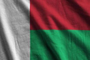 Madagascar flag with big folds waving close up under the studio light indoors. The official symbols and colors in banner photo