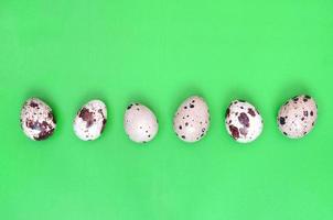 Quail eggs on a light green surface, top view, empty place for t photo