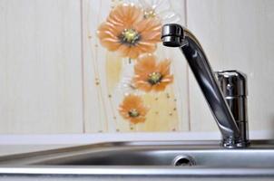 Empty clean silvery kitchen sink and water faucet close up photo