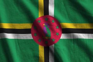 Dominica flag with big folds waving close up under the studio light indoors. The official symbols and colors in banner photo