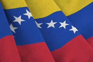 Venezuela flag with big folds waving close up under the studio light indoors. The official symbols and colors in banner photo