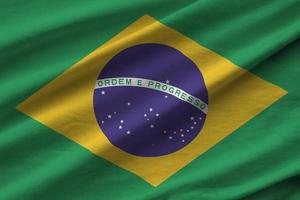 Brazil flag with big folds waving close up under the studio light indoors. The official symbols and colors in banner photo