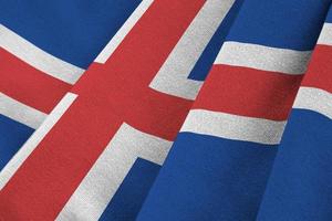 Iceland flag with big folds waving close up under the studio light indoors. The official symbols and colors in banner photo