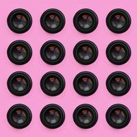 A few camera lenses with a closed aperture lie on texture background of fashion pastel pink color paper in minimal concept. Abstract trendy pattern photo