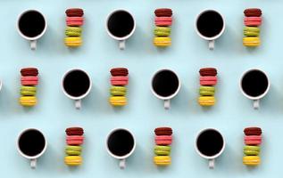 un patrón de muchos coloridos macarrones de pastel de postre y tazas de café en la moderna vista superior de fondo azul pastel. composición plana foto