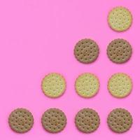 patrón de galletas marrones sobre un fondo rosa. concepto mínimo de moda de comida y postre. plano abstracto, vista superior foto