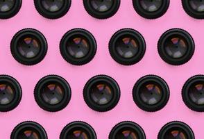 A few camera lenses with a closed aperture lie on texture background of fashion pastel pink color paper in minimal concept. Abstract trendy pattern photo